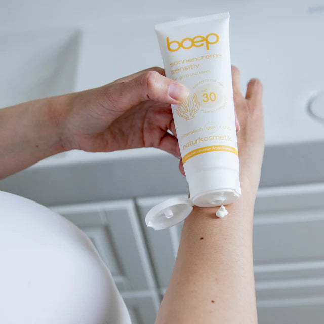 Person trägt Sonnencreme aus einer Tube mit der Aufschrift "boep" auf den Arm auf.
