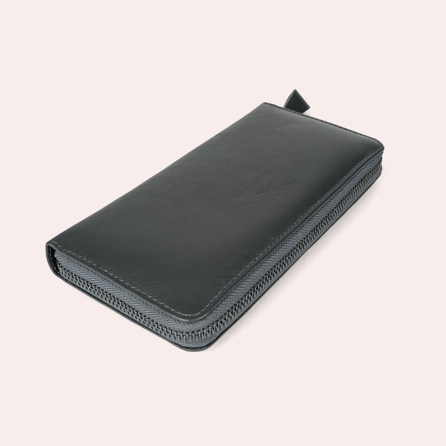 Ein schwarzes Lederportemonnaie mit Reißverschluss ist geschlossen und leicht schräg auf einem schlichten hellen Hintergrund positioniert.