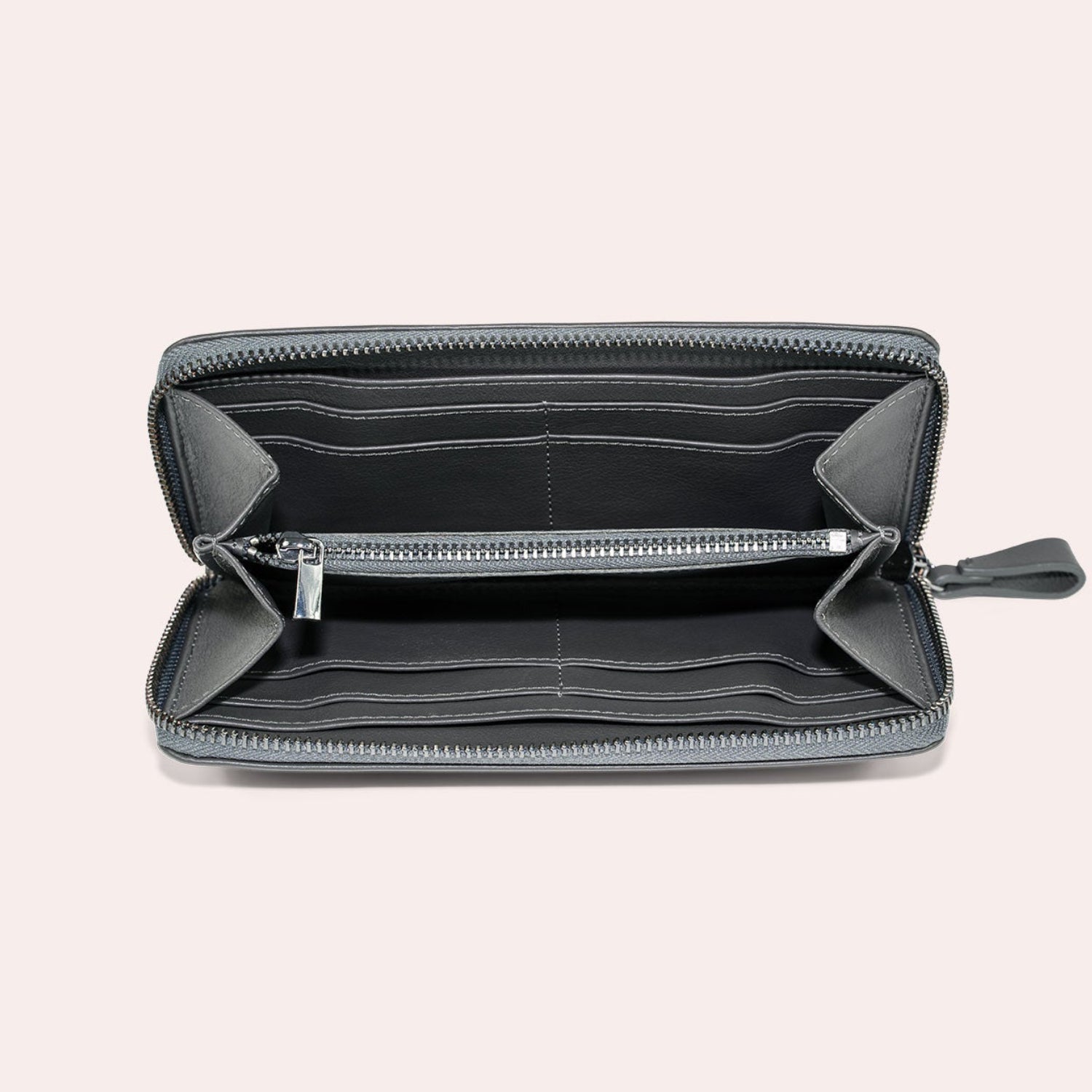 Eine graue Brieftasche mit Reißverschluss ist geöffnet und zeigt mehrere Kartenfächer, ein zentrales Münzfach mit Reißverschluss und Fächer für Geldscheine, alles vor einem schlichten hellen Hintergrund.
