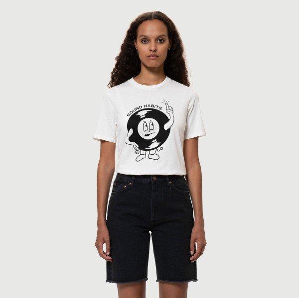 Frau mit lockigem Haar trägt ein weißes T-Shirt mit einem Cartoon-Aufdruck und dunklen Jeansshorts.