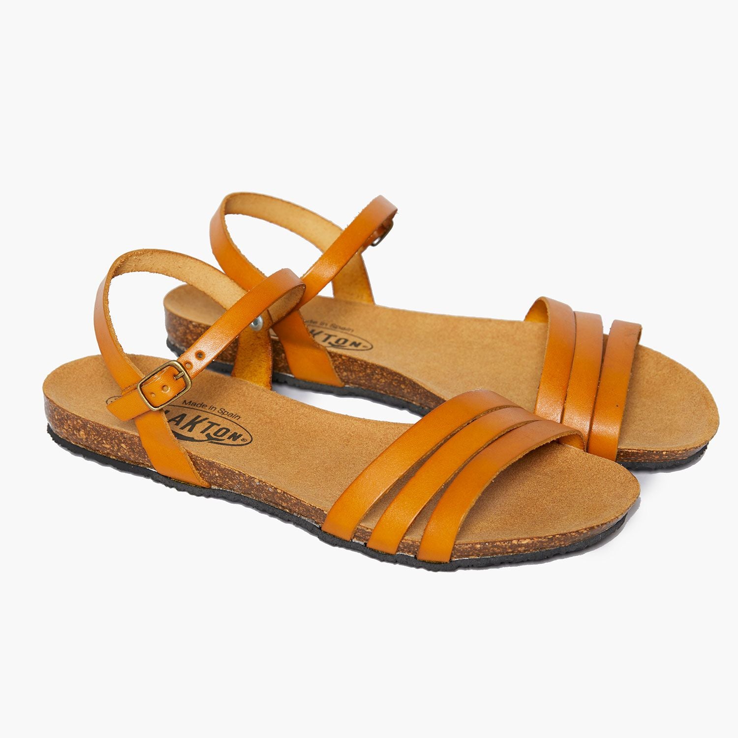 Braune Ledersandalen mit Riemen und Korksohle auf weißem Hintergrund.