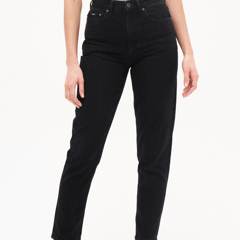 Person trägt eine schwarze Jeans, die knapp unter der Taille endet, vor einem weißen Hintergrund.