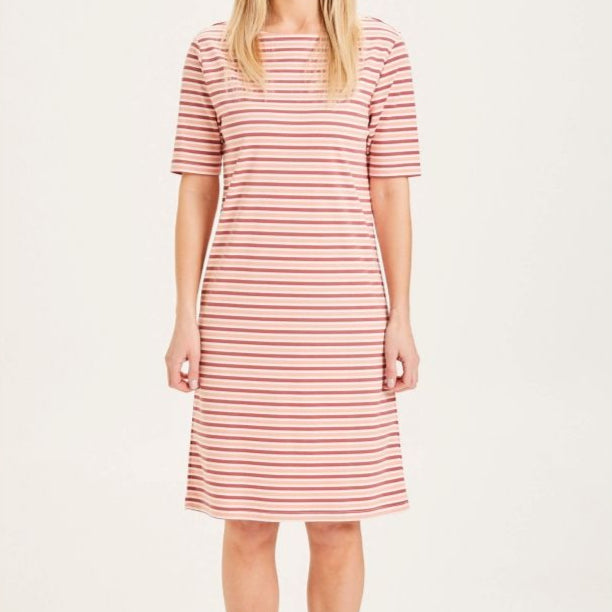 Person in a pink and white stripe dress, standing against a plain background.