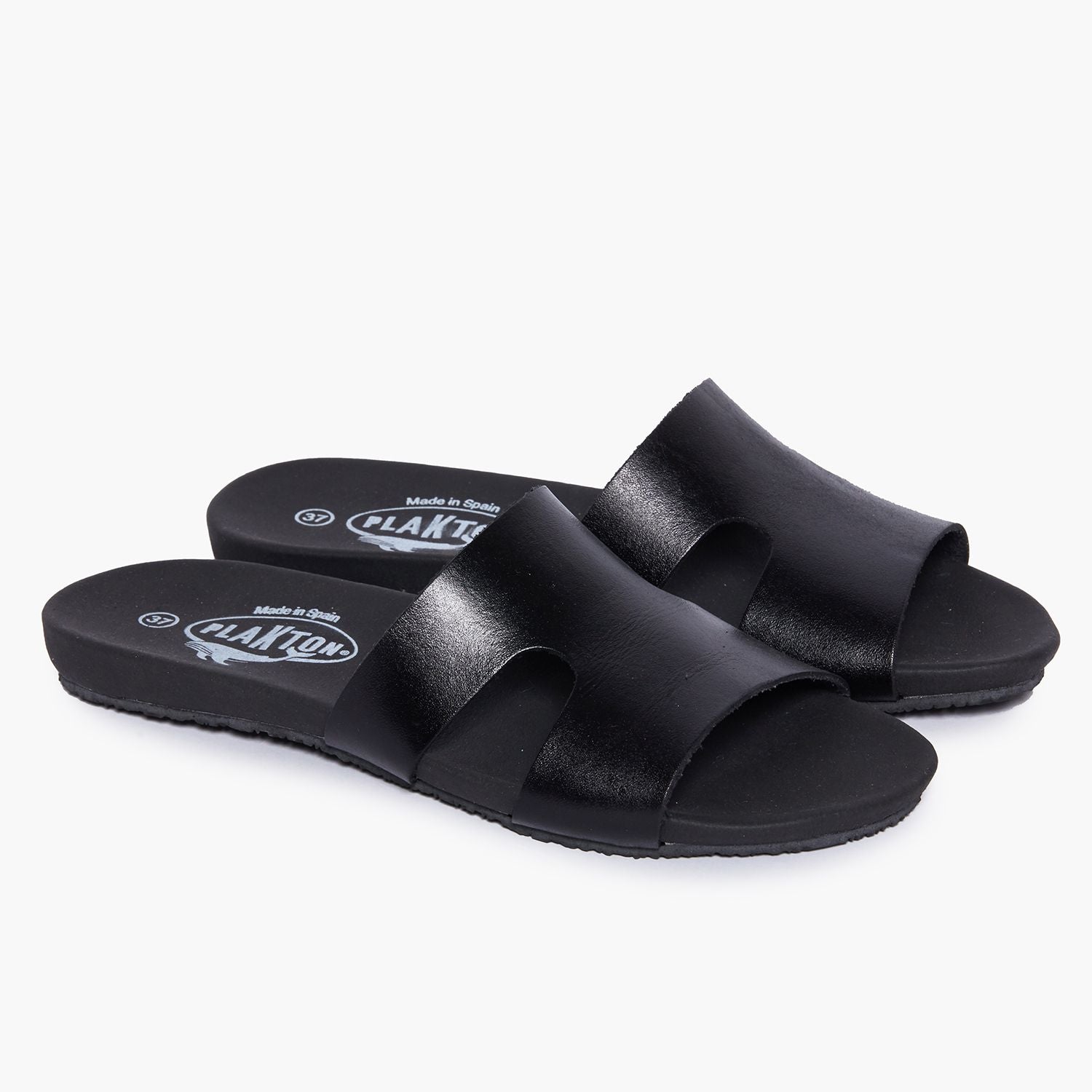 Ein Paar schwarzer Sandalen mit breiten Riemen und schlichter Sohle auf weißem Hintergrund.