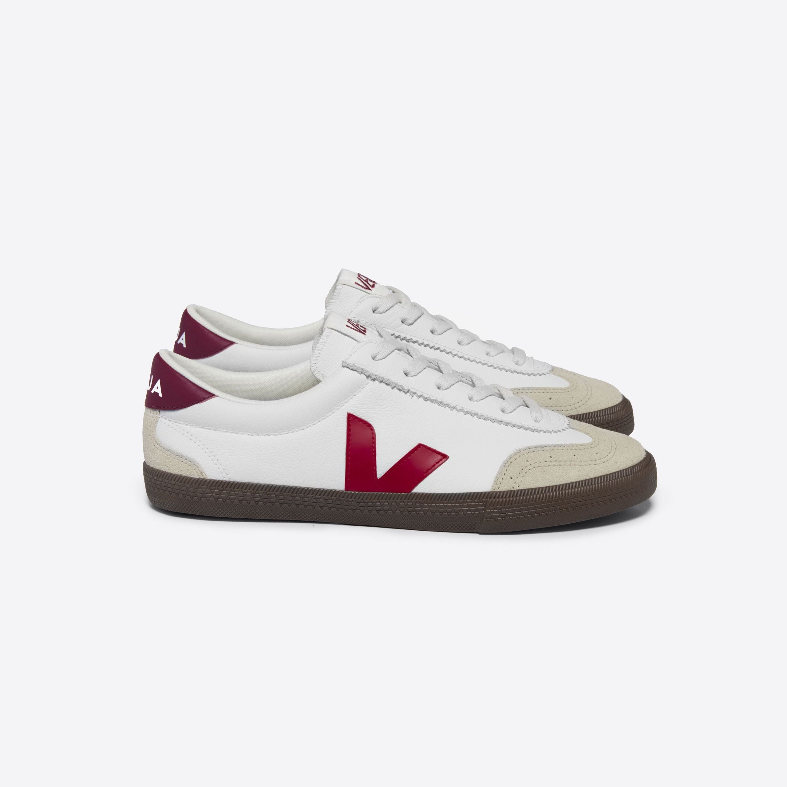 Weiße Sneakers mit bordeauxfarbenem Logo und brauner Sohle, in einer Seitenansicht dargestellt.