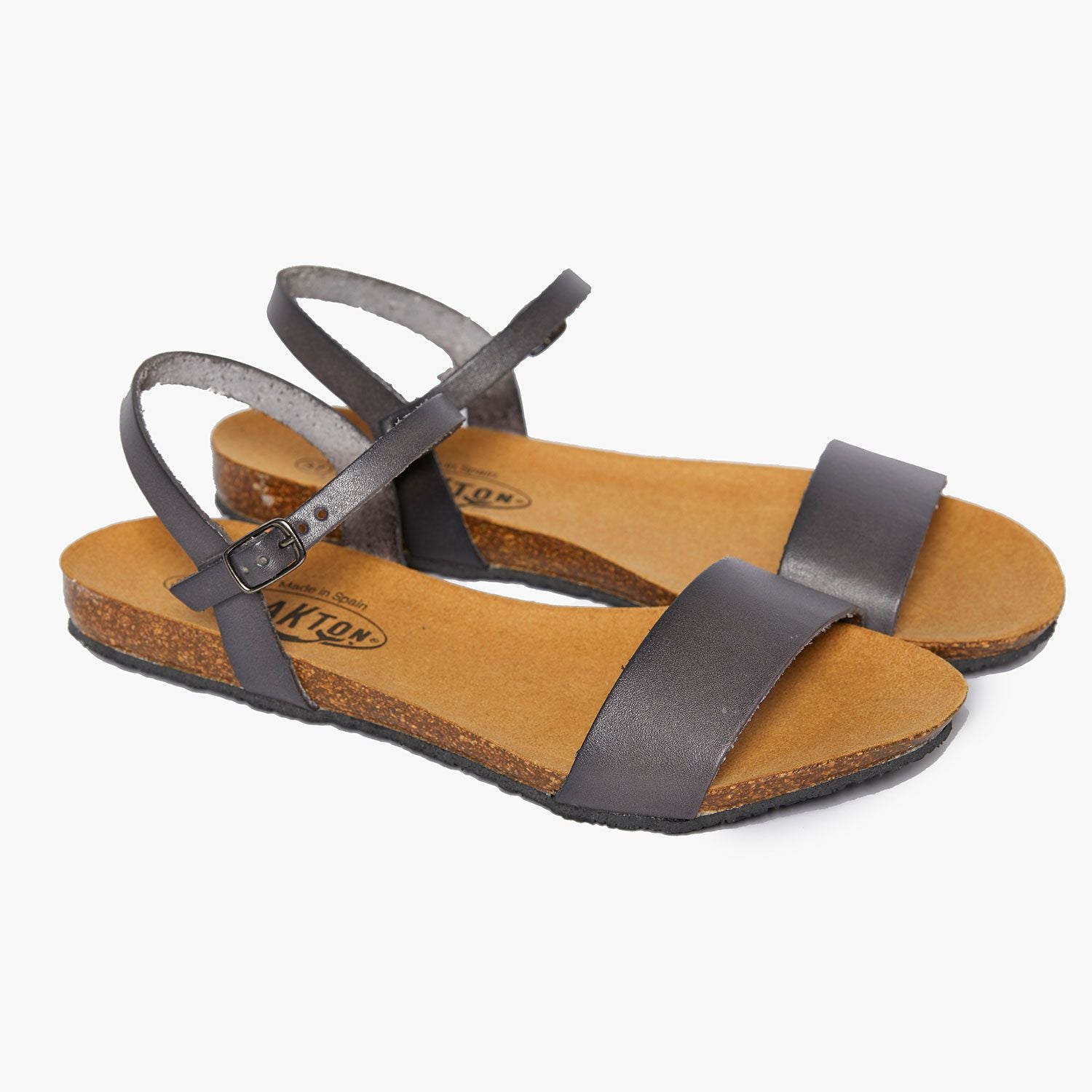 Graue Ledersandalen mit Schnallenriemen und Korksohle auf weißem Hintergrund.