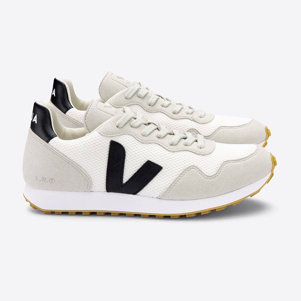 Weiße Sneaker mit schwarzem "V"-Logo an der Seite, schwarzen Details an der Ferse und beiger Sohle auf grauem Hintergrund.