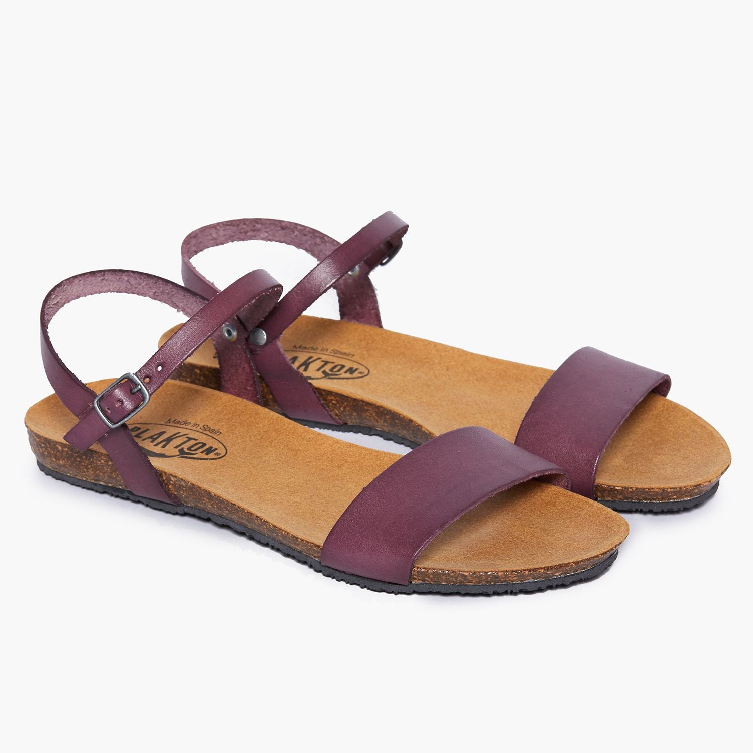 Lila Sandalen mit einem flachen Korkfußbett und verstellbaren Riemen auf weißem Hintergrund.