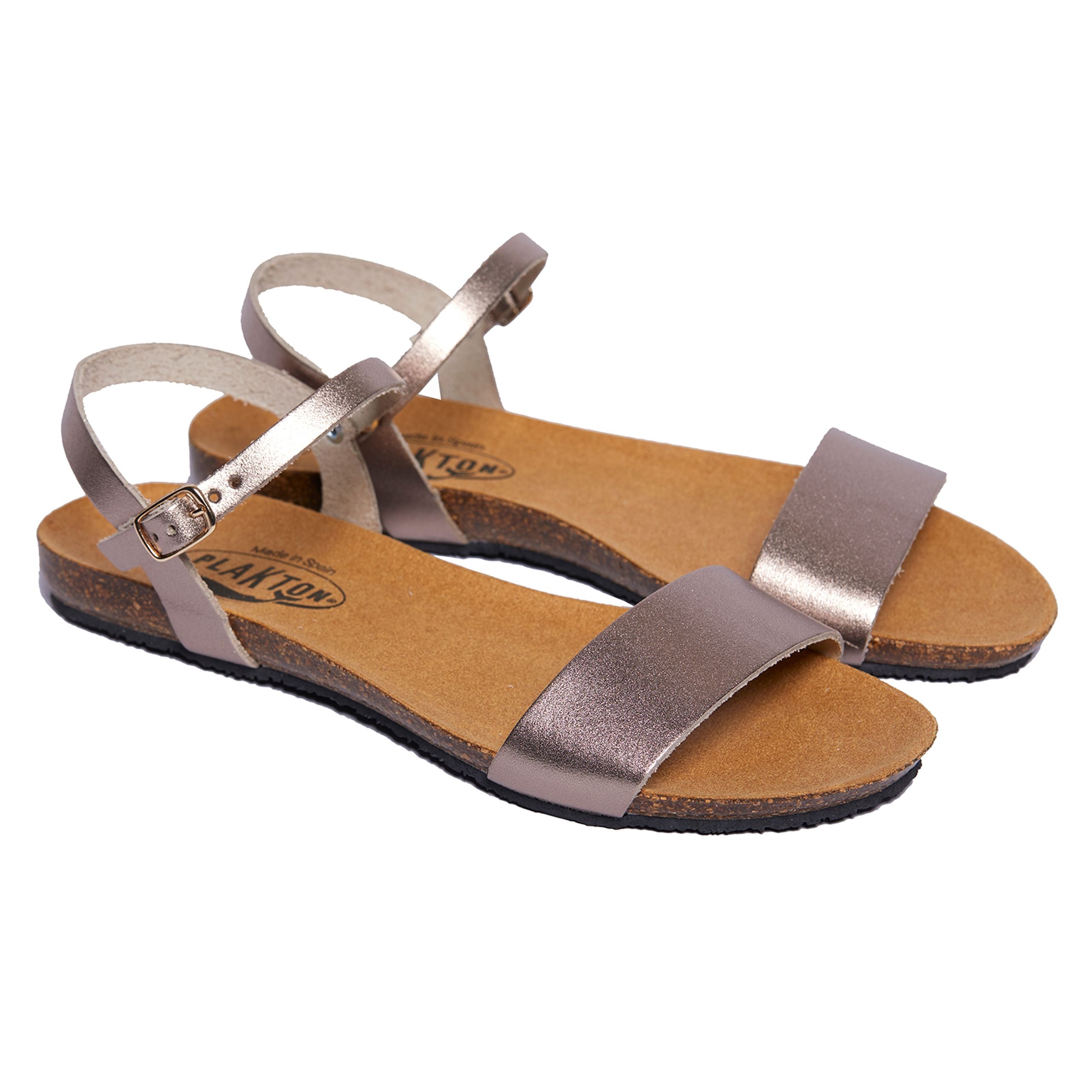 Braune flache Sandalen mit Riemen und Schnalle, auf hellbrauner Sohle, isoliert vor weißem Hintergrund.