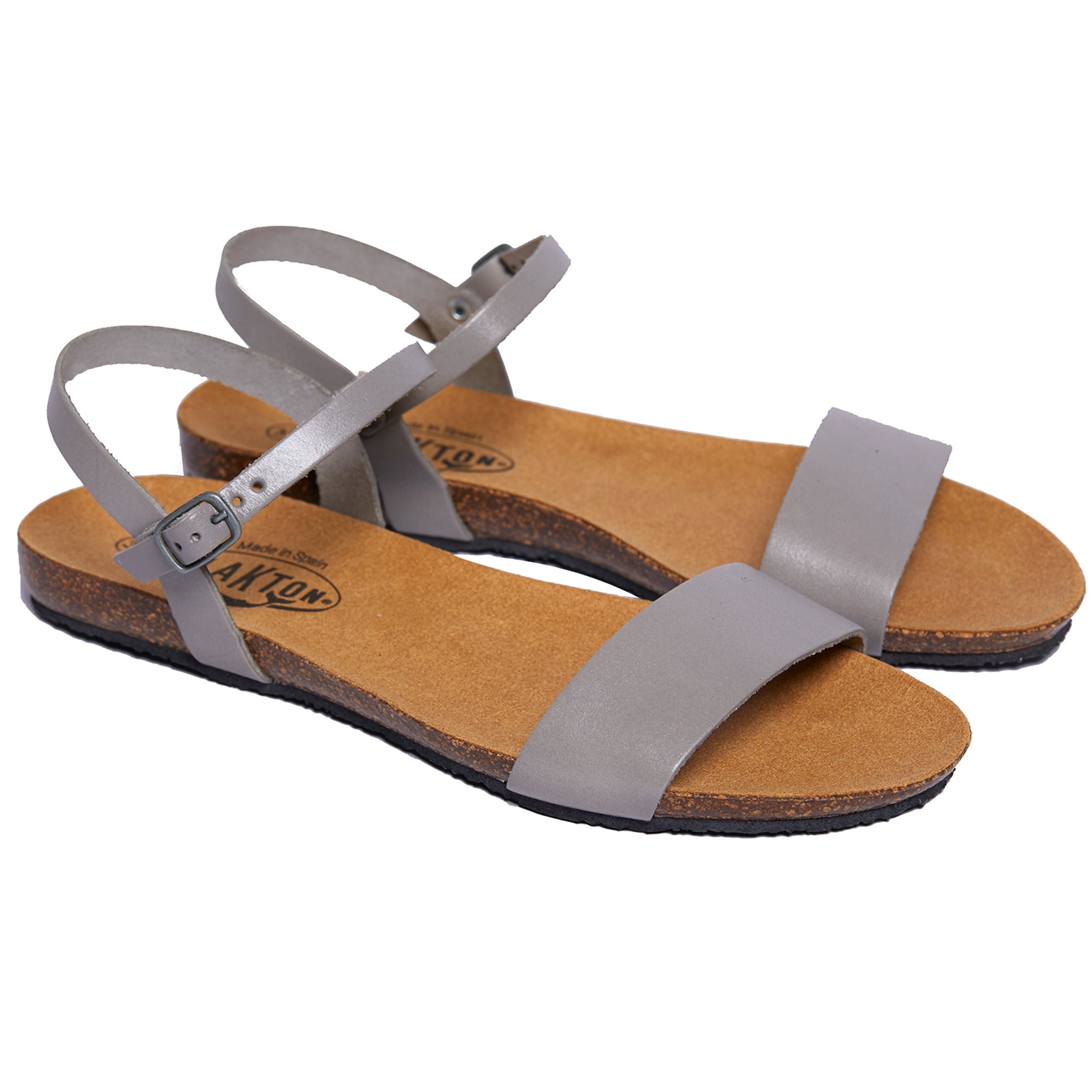 Graue Sandalen mit Riemchen und Schnallen aus Leder auf einer braunen Sohle.