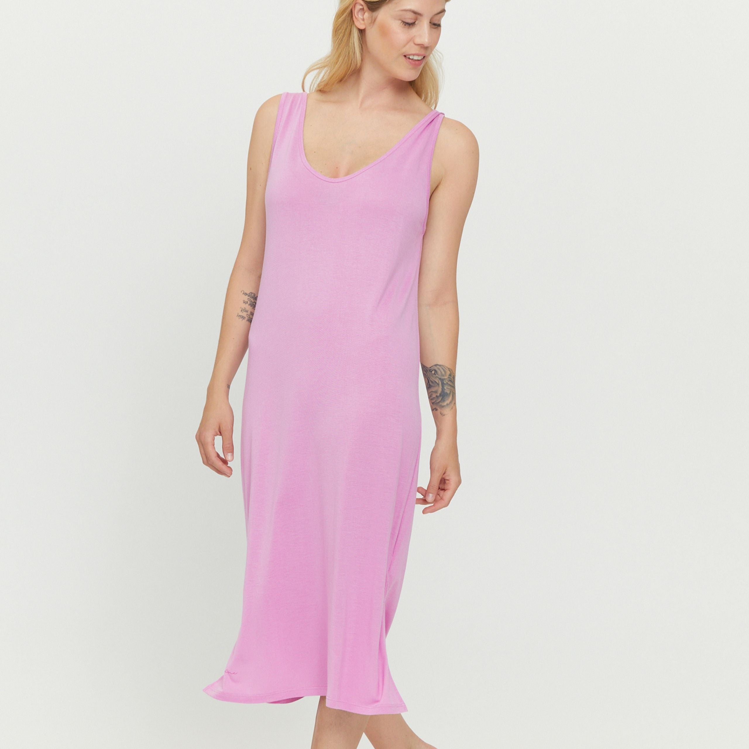 Person in einem rosa ärmellosen Kleid vor weißem Hintergrund.