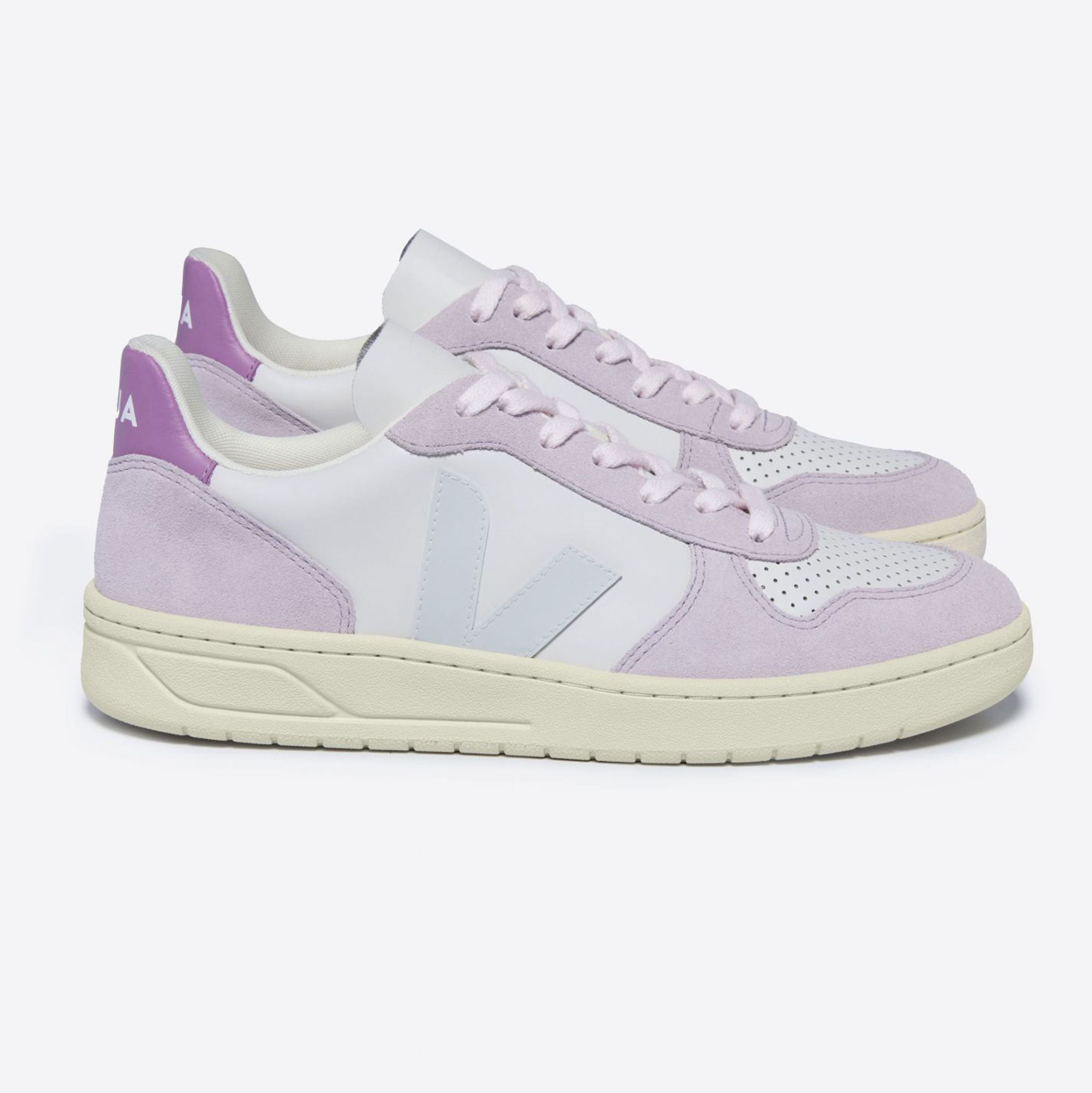 Lila und weiße Sneaker mit beigem Schuhsohle, seitlichem Logo und perforiertem Obermaterial, auf grauem Hintergrund.