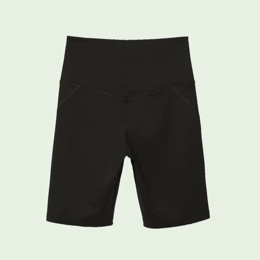 Schwarze Radlerhose mit hohem Bund vor einem hellgrünen Hintergrund.
