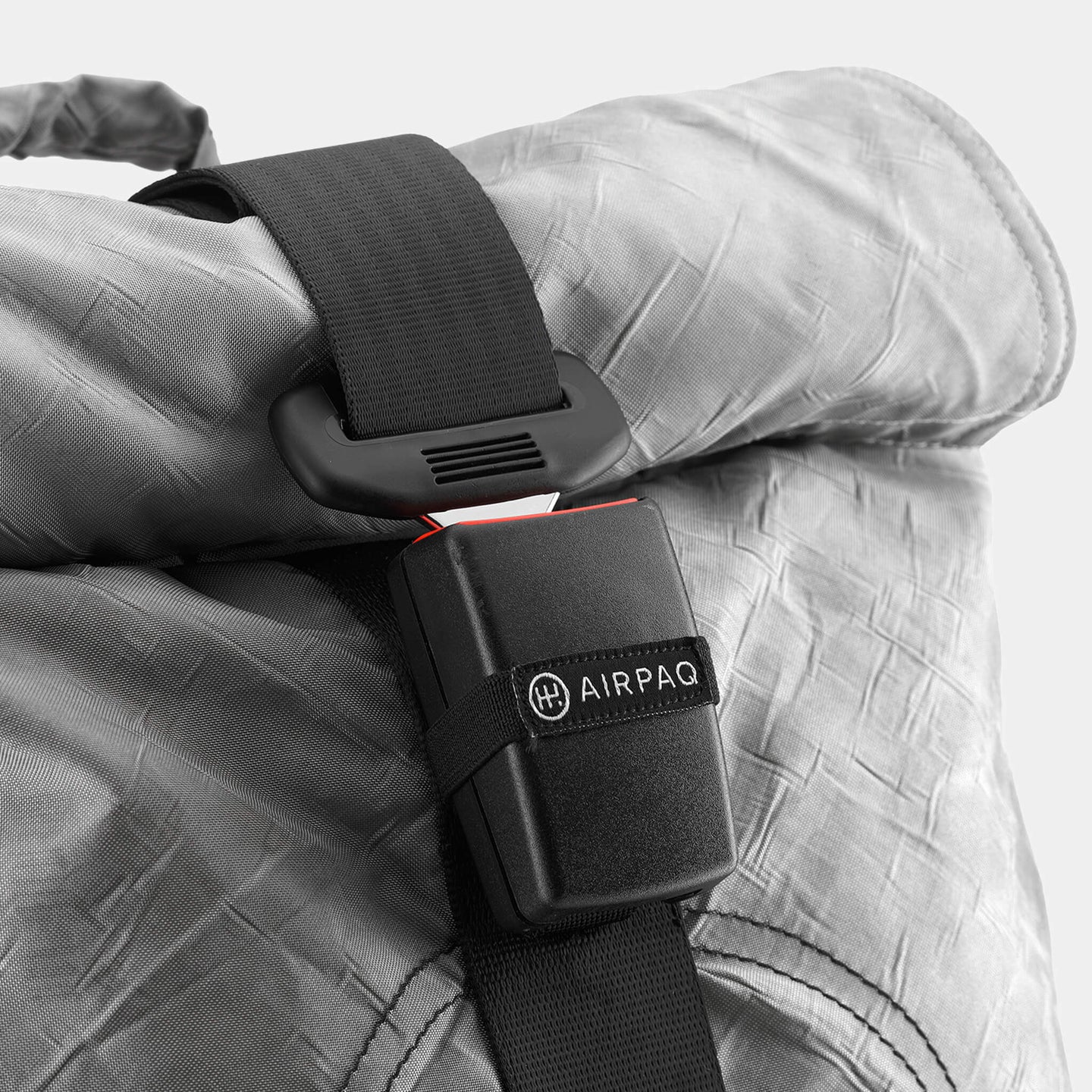 Nahaufnahme eines grauen Rucksacks mit einem schwarzen, verschließbaren Gurt mit dem Logo "AIRPAQ".