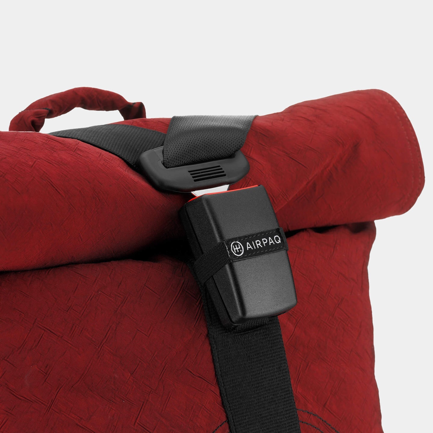 Roter Rucksack mit schwarzem Gurtband und Klickverschluss, Marke "AIRPAQ" sichtbar.