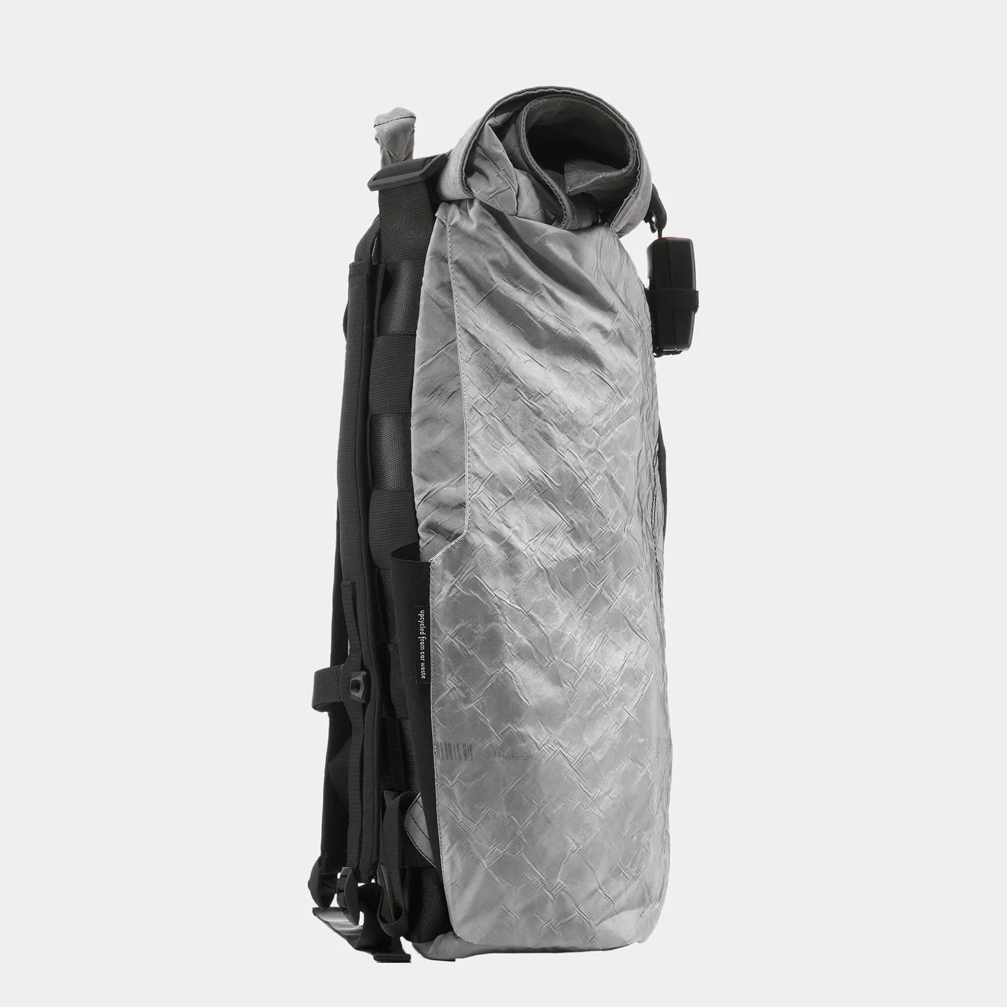 Grauer, modern gestalteter Rucksack im Profil, mit einem strukturierten Stoff und schwarzen Details vor weißem Hintergrund.