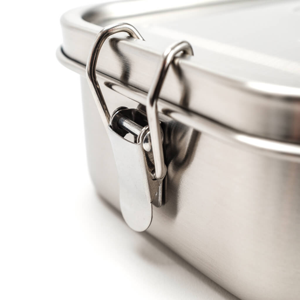 Metall-Lunchbox mit Kunststoffdeckel und Metallverschluss, Makroaufnahme des Verschlusses auf weißem Hintergrund.