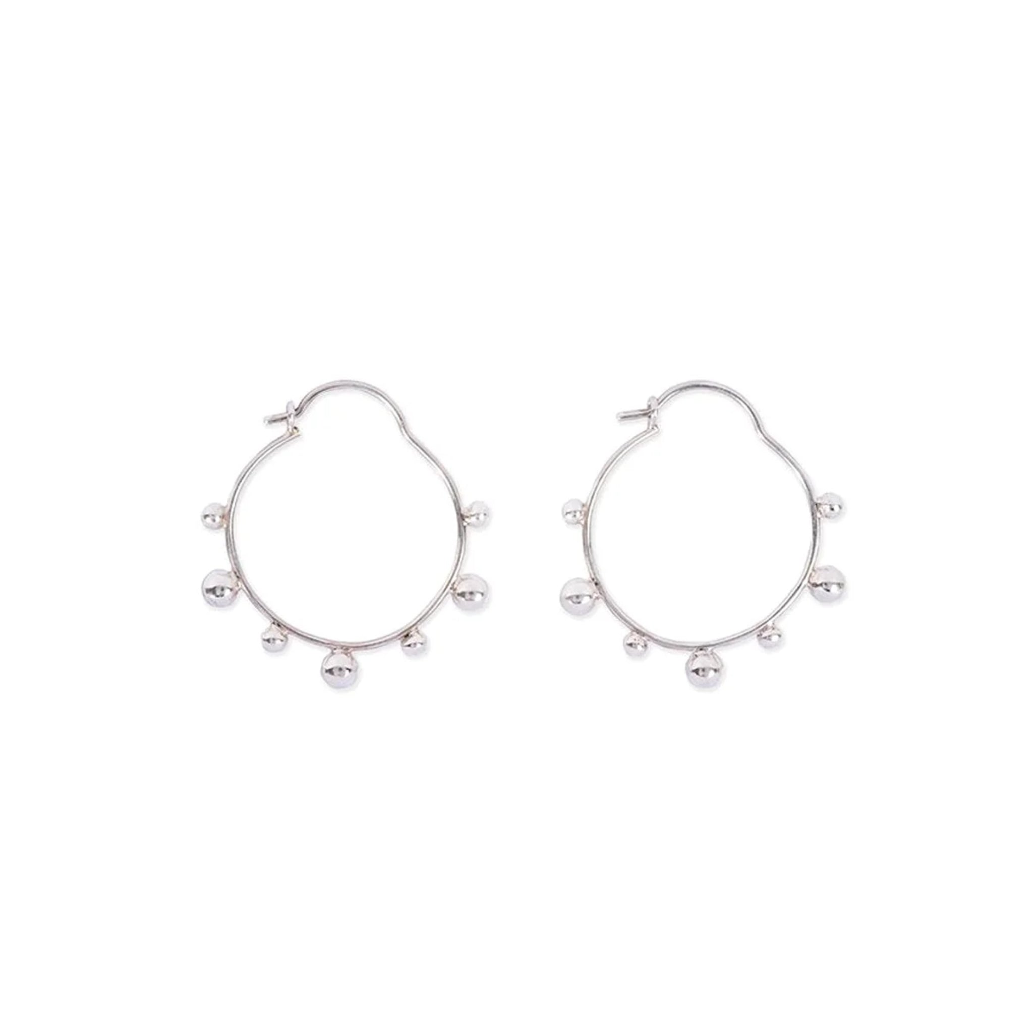 Silberne Creolen mit kleinen Kugeln entlang des Rings, auf weißem Hintergrund liegend.