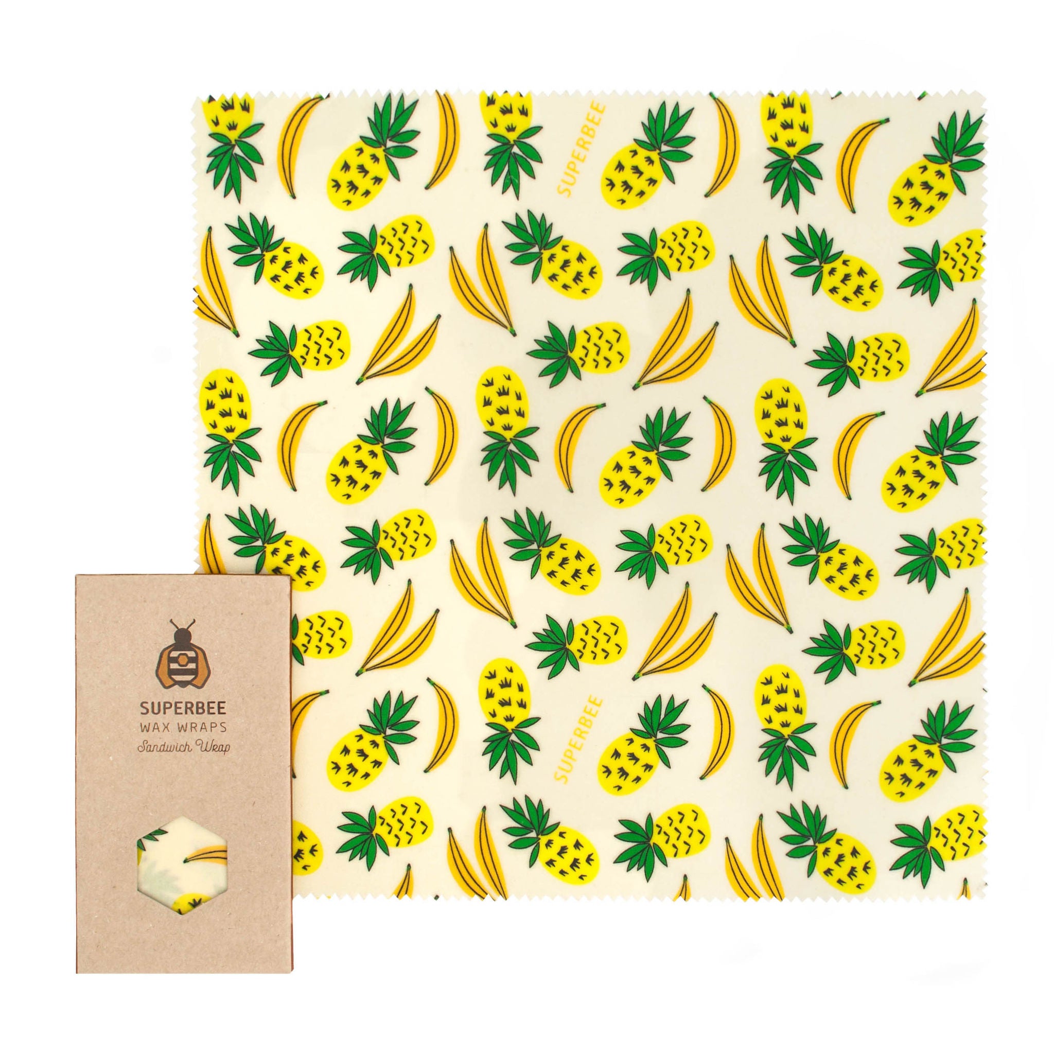 Eine wiederverwendbare Bienenwachsfolie mit einem gelben Ananas- und Bananenmuster neben einer braunen Kartonverpackung der Marke SuperBee mit einem sechseckigen Fenster, das die Folie zeigt.