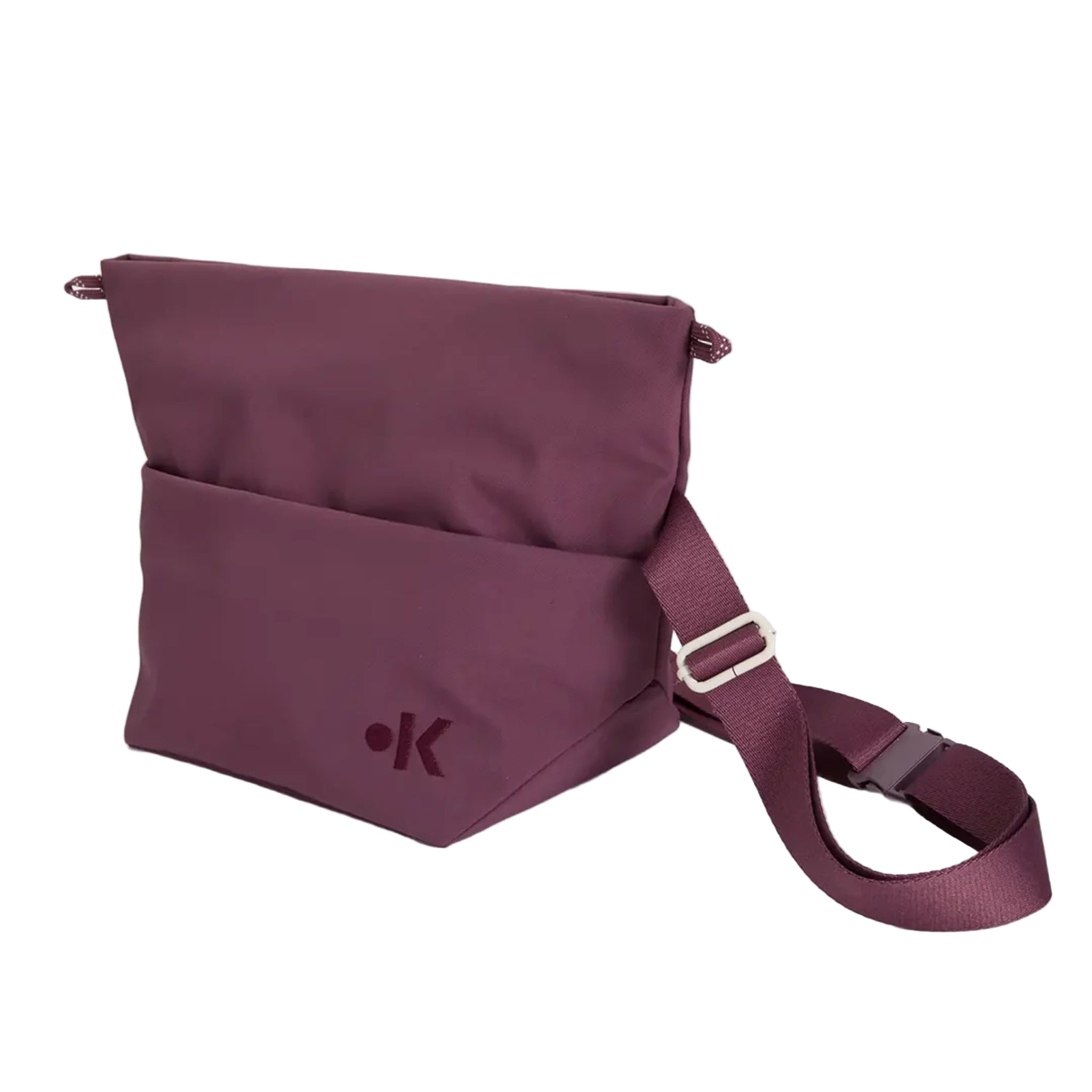 Eine kastanienbraune Umhängetasche mit einer Vordertasche, einem verstellbaren Riemen und einem kleinen Punkt- und Buchstaben-K-Logo auf der unteren Vorderseite. Die Tasche ist vor einem schlichten weißen Hintergrund abgebildet.