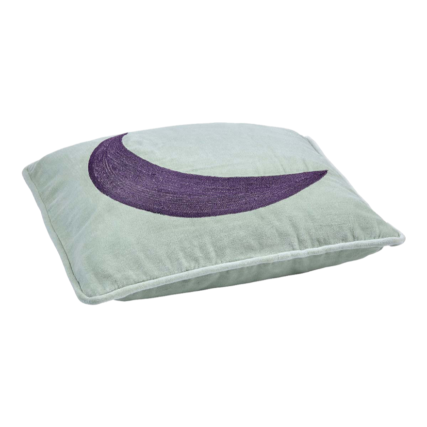 Grünes Kissen mit einer lila Mondsichel darauf.