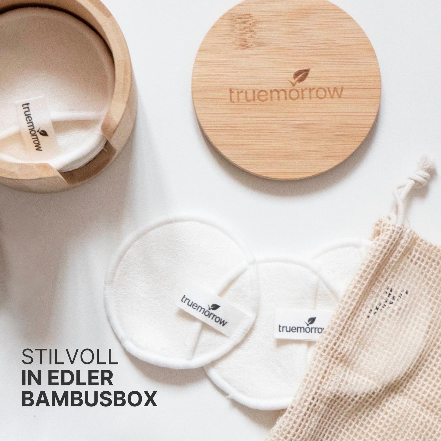 Runde Baumwollpads mit truemorrow-Logo, stilvoll präsentiert in einer Bambusbox mit Netzbeutel auf weißem Hintergrund.