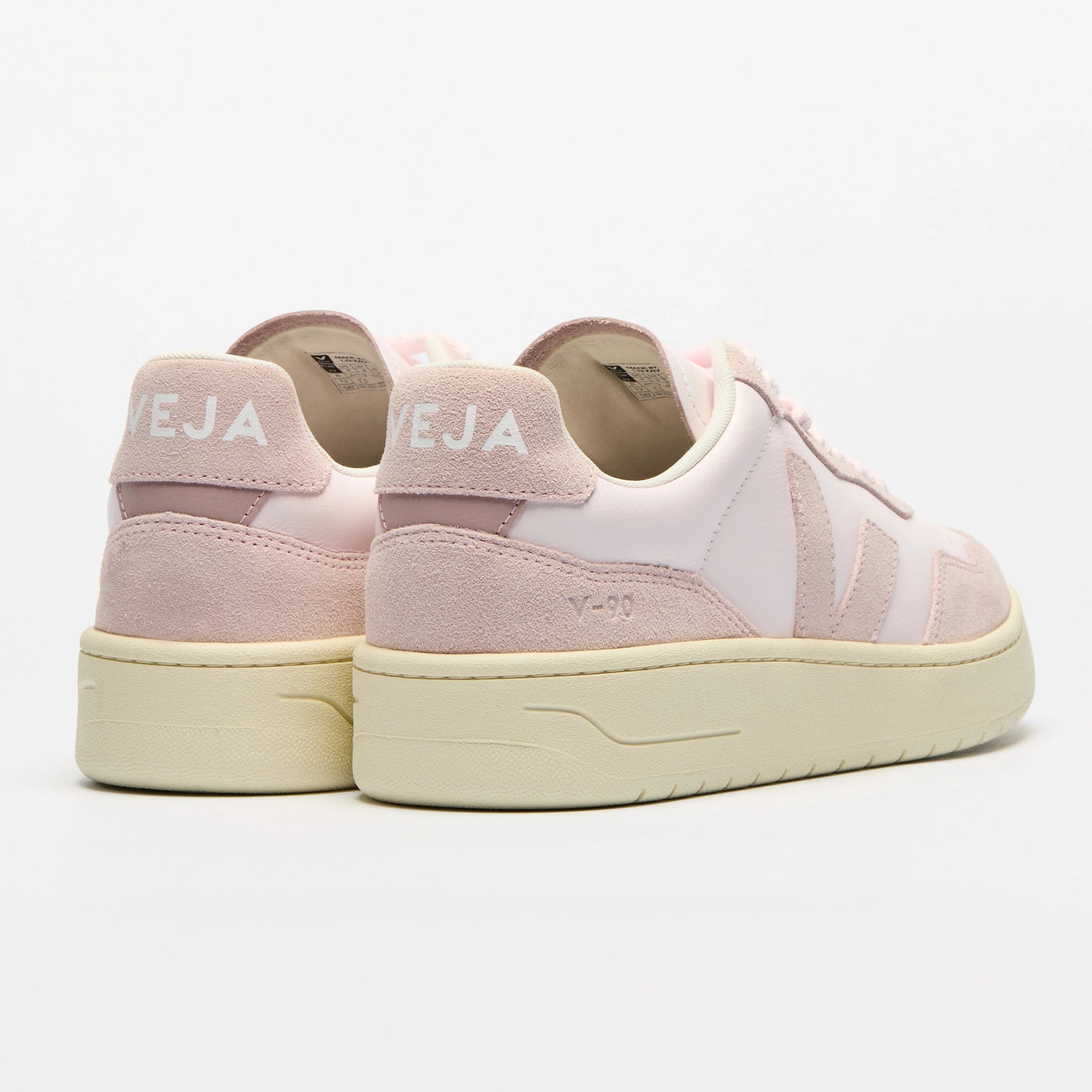 Ein Paar hellrosa und cremefarbene VEJA-Sneaker mit Wildleder- und Ledereinsätzen, mit VEJA-Branding an der Ferse und einer dicken beigen Sohle auf weißem Hintergrund.