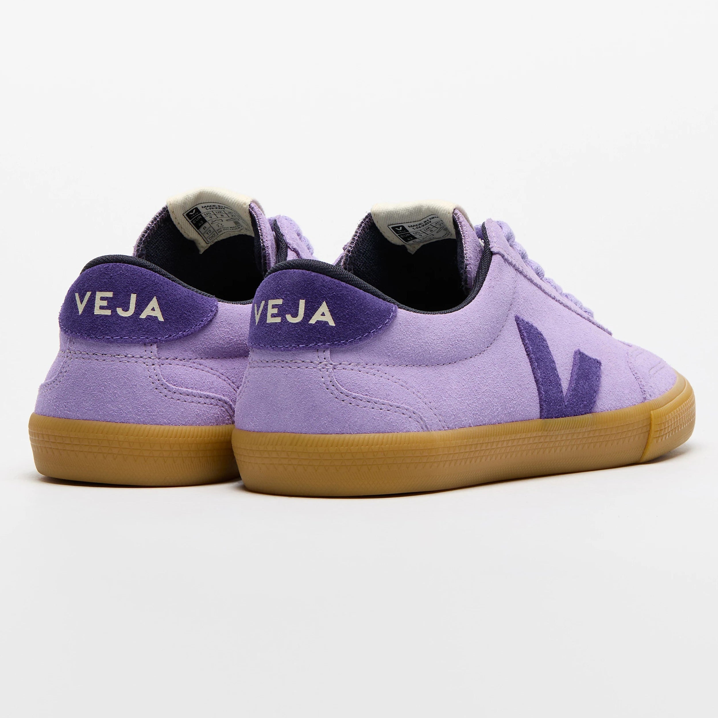 Ein Paar lilafarbene Veja-Turnschuhe mit Gummisohle, lilafarbenem V-Logo an der Seite und weißem VEJA-Schriftzug an der Ferse auf einem schlichten weißen Hintergrund.