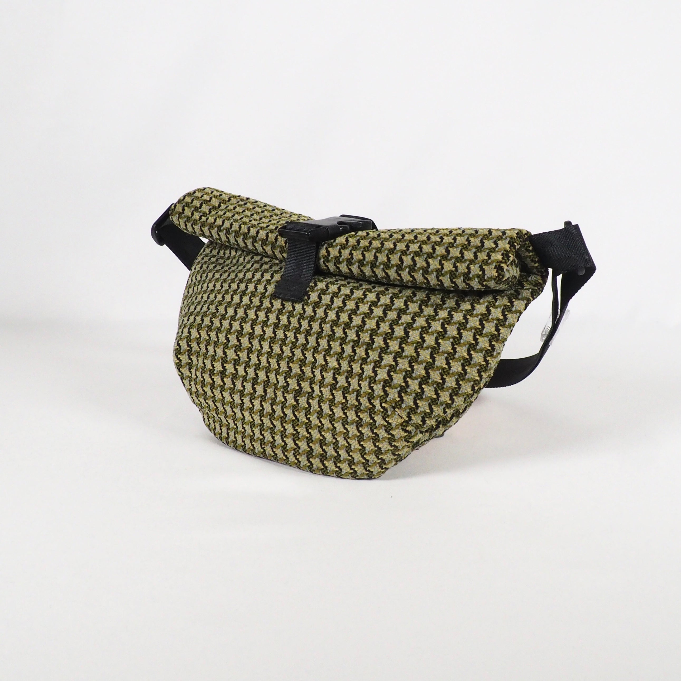 Grüne Umhängetasche mit schwarzem Riemen und geometrischem Muster auf weißem Hintergrund.