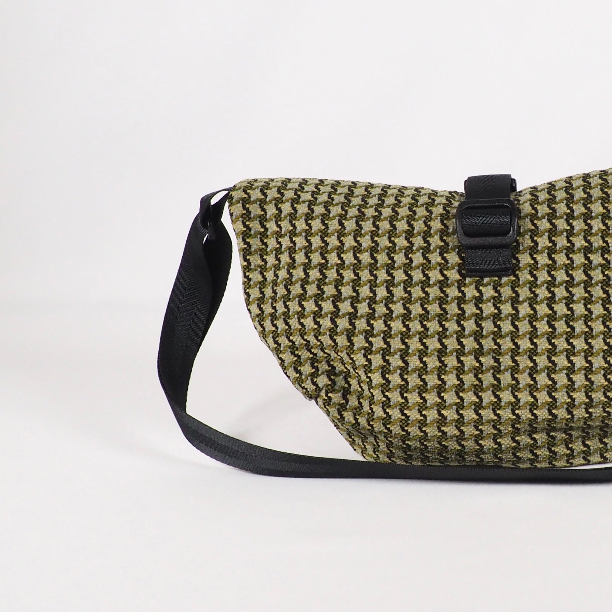 Braune und schwarze Umhängetasche mit Muster und schwarzem Schulterriemen auf weißem Hintergrund.