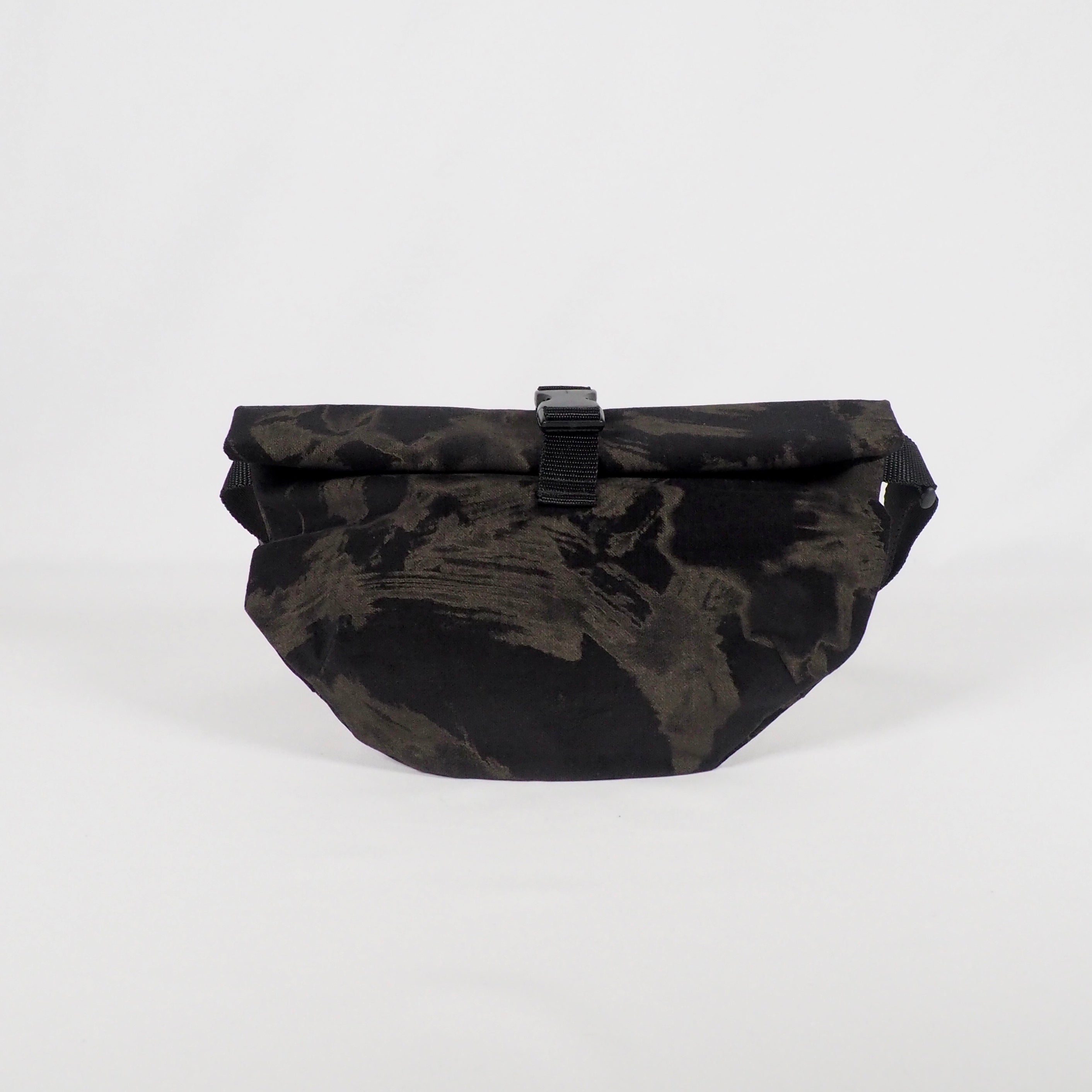 Schwarze Bauchtasche mit abstraktem Muster und Verschluss, vor weißem Hintergrund.