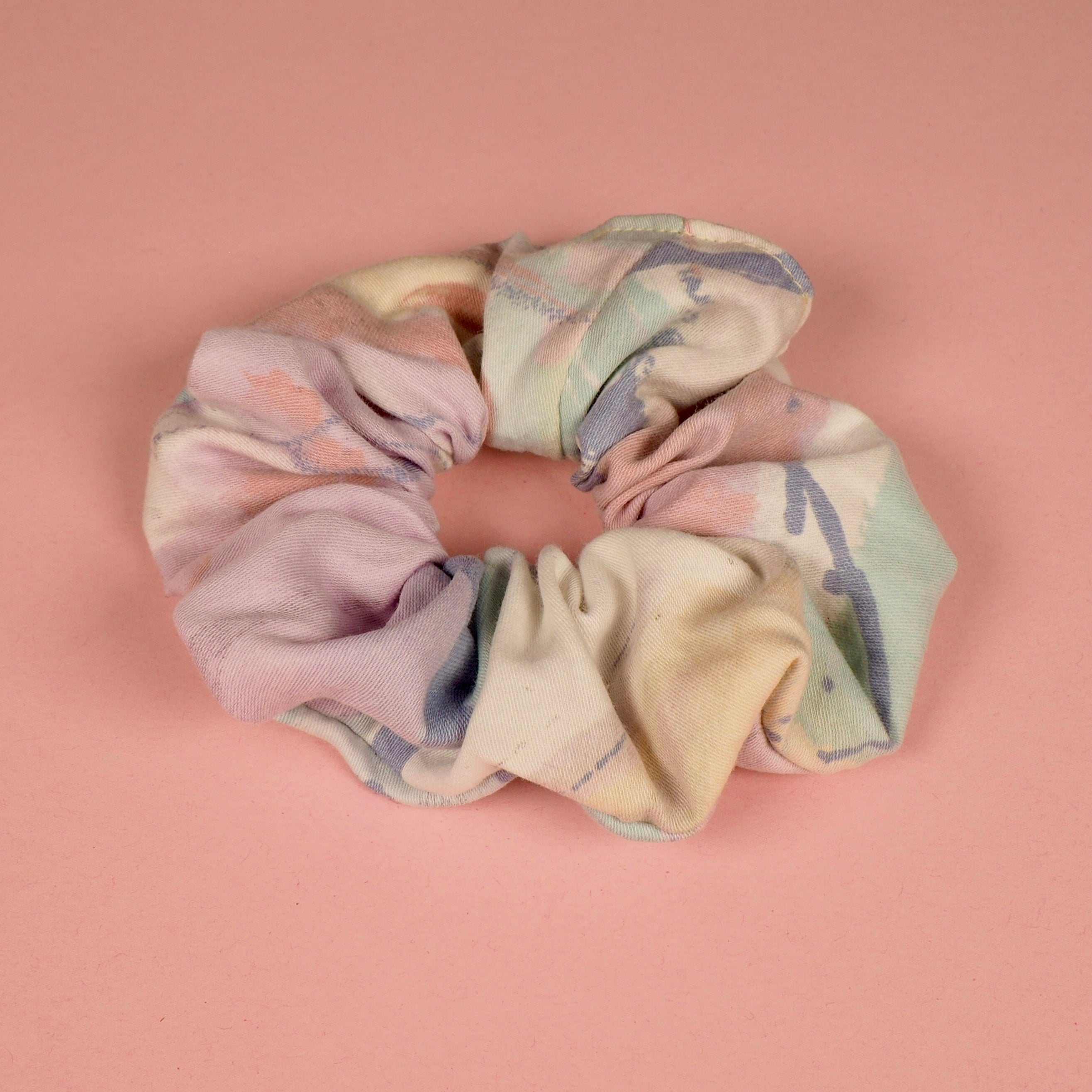 Buntes, pastellfarbenes Haargummi mit Batikmuster auf rosa Hintergrund.