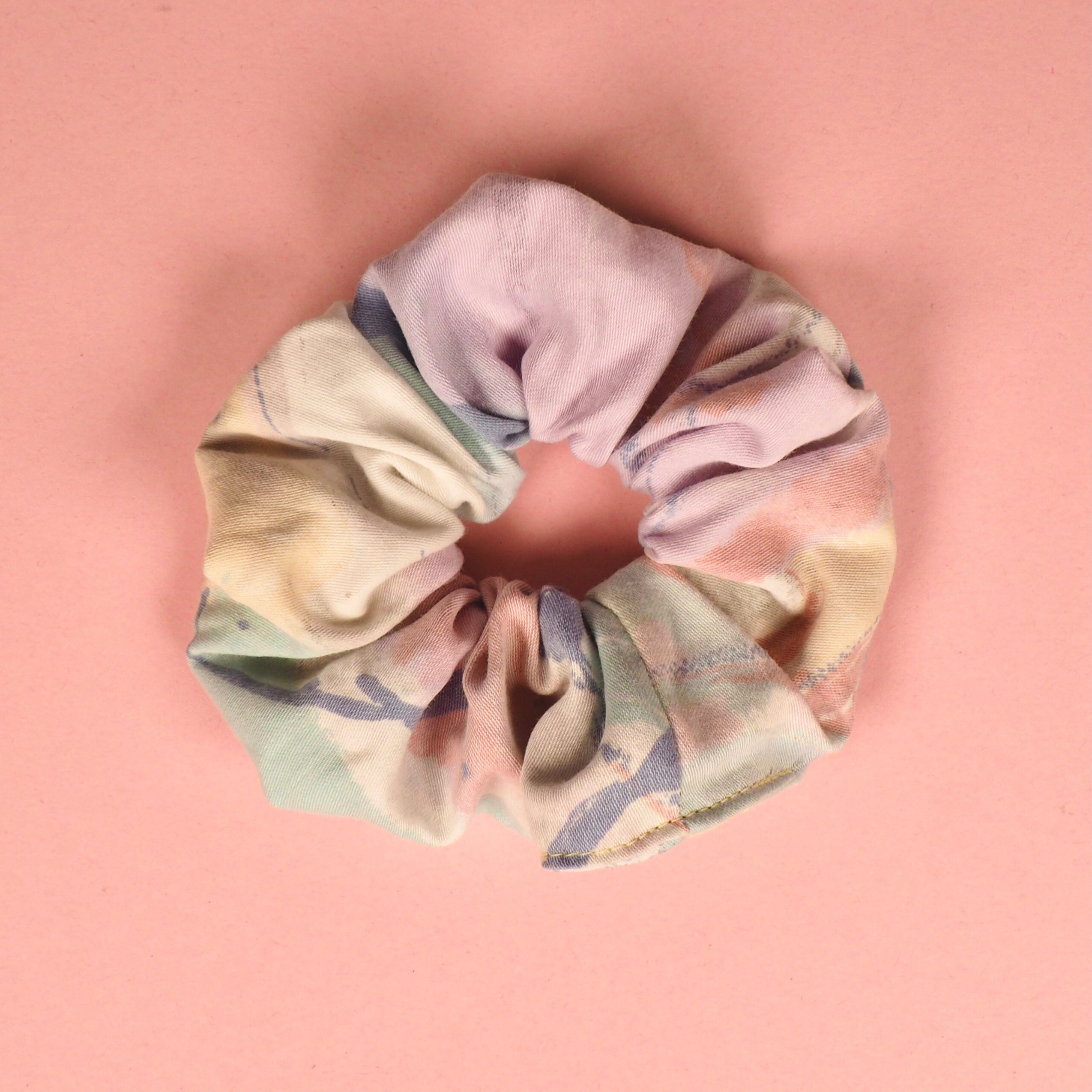 Ein buntes Haargummi liegt auf einem rosa Hintergrund.