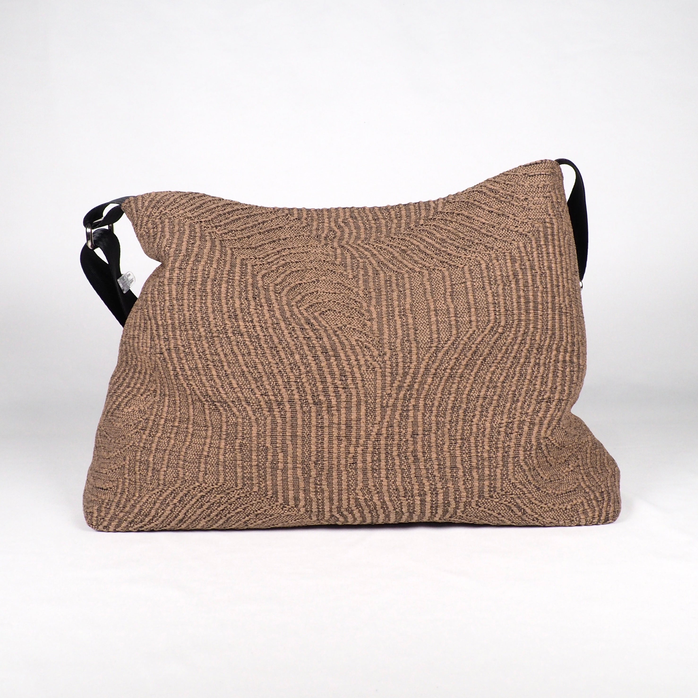 Braune Stofftasche mit geometrischem Muster und schwarzem Schultergurt vor weißem Hintergrund.