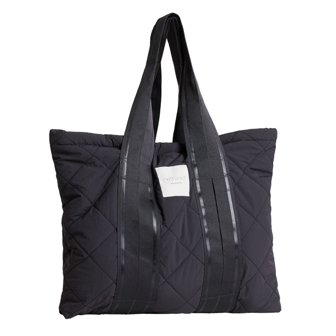 Schwarze gesteppte Tragetasche mit langen Griffen und einem weißen Etikett in der Mitte.