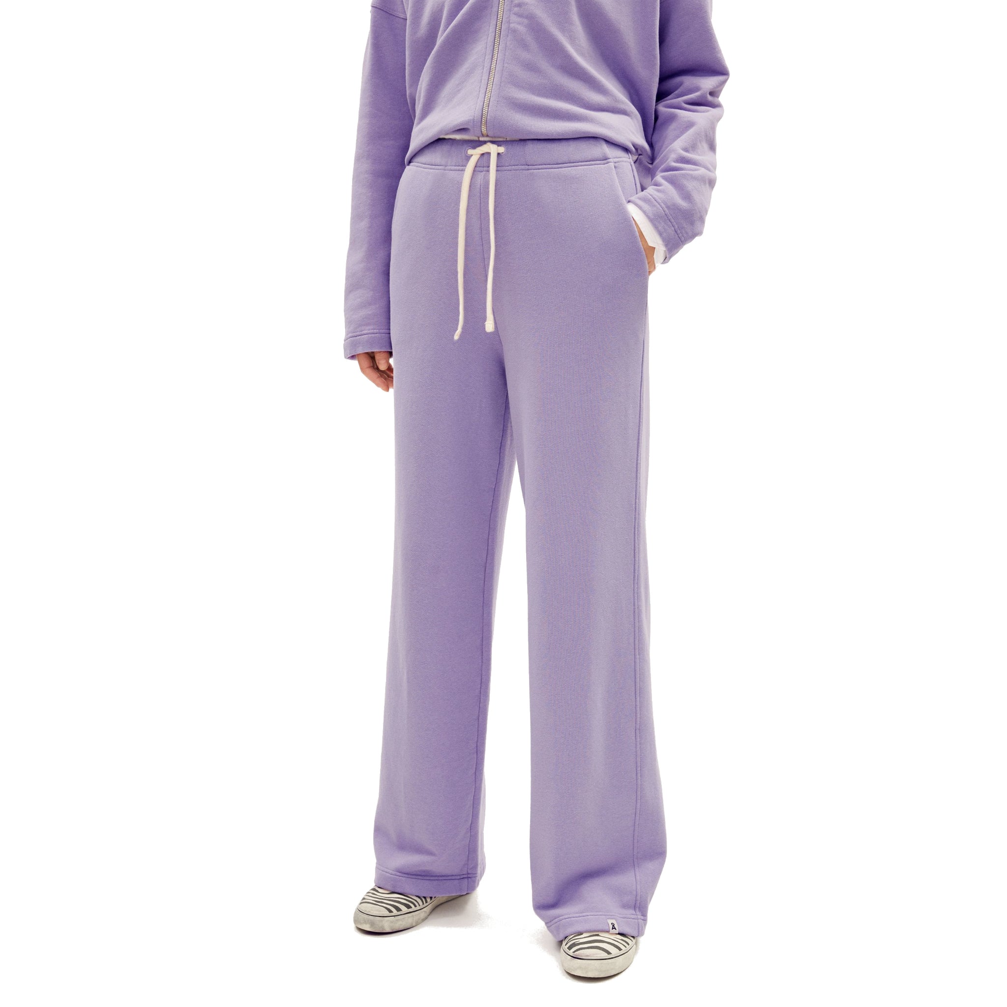 Person in lila Jogginganzug mit weißen Schnürsenkeln, gestreifte Schuhe, keine sichtbaren Gesichter.