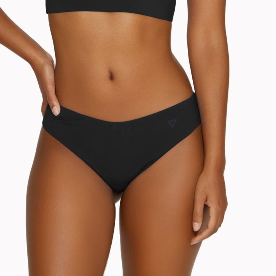 Frau trägt schwarzen Bikini und posiert vor einem weißen Hintergrund, Fokus auf Taille und Hüfte.
