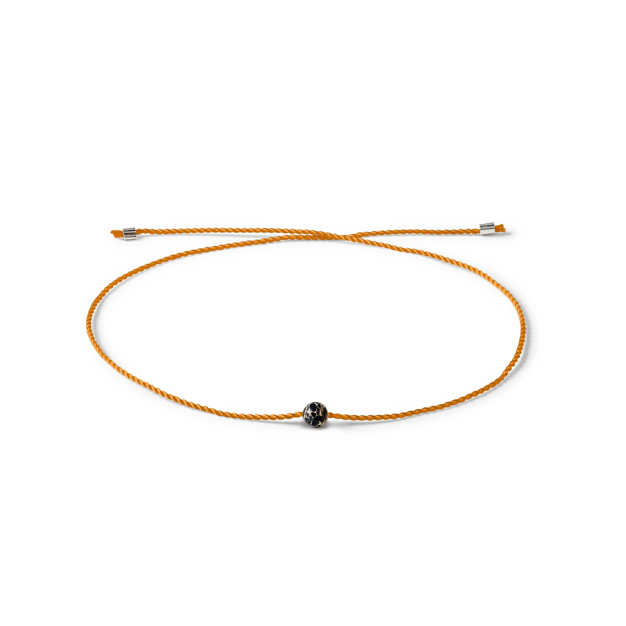 Orange Kordelarmband mit schwarzem, gemustertem Perlenanhänger auf weißem Hintergrund.