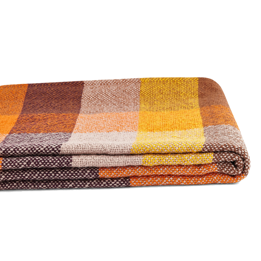 Eine gefaltete Decke mit einem Schachbrettmuster in Orange-, Gelb-, Braun- und Beigetönen auf weißem Grund.