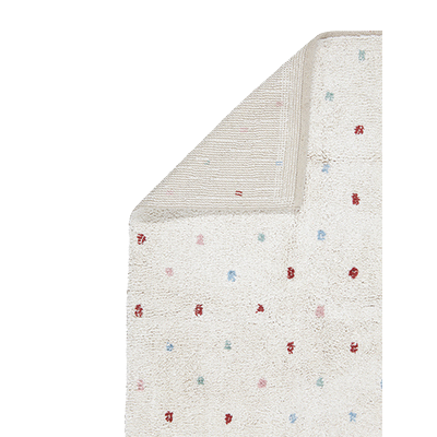 Ein cremefarbener Teppich mit kleinen, verstreuten roten, blauen und rosa Punkten. Eine Ecke ist umgeschlagen und zeigt eine gestreifte beige Unterseite.