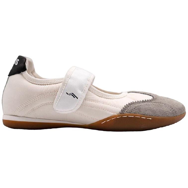 Ein weißer Kampfsportschuh mit Klettverschluss, Zehenkappe aus Wildleder, schwarzem Absatz und brauner flacher Gummisohle, dargestellt in einer Seitenansicht.