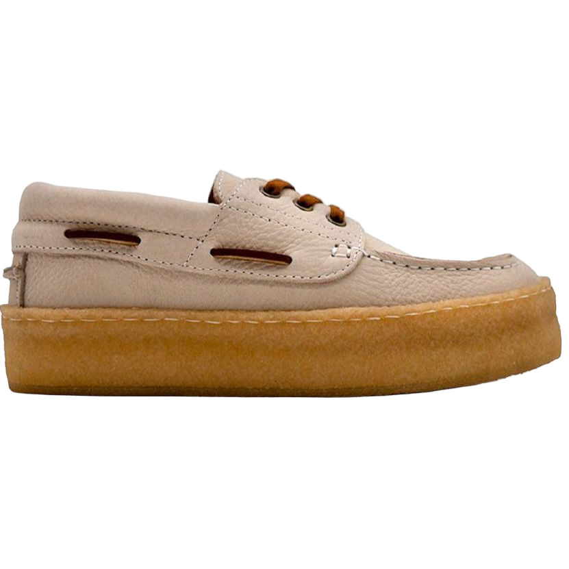 Ein Bootsschuh aus beigem Leder mit braunen Schnürsenkeln und Ösen, einer dicken, hellbraunen Kreppsohle und sichtbaren Nähten an Schaft und Sohle.
