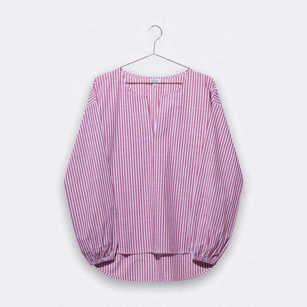 Gestreifte Bluse in Rosa und Weiß, auf einem Kleiderbügel hängend.