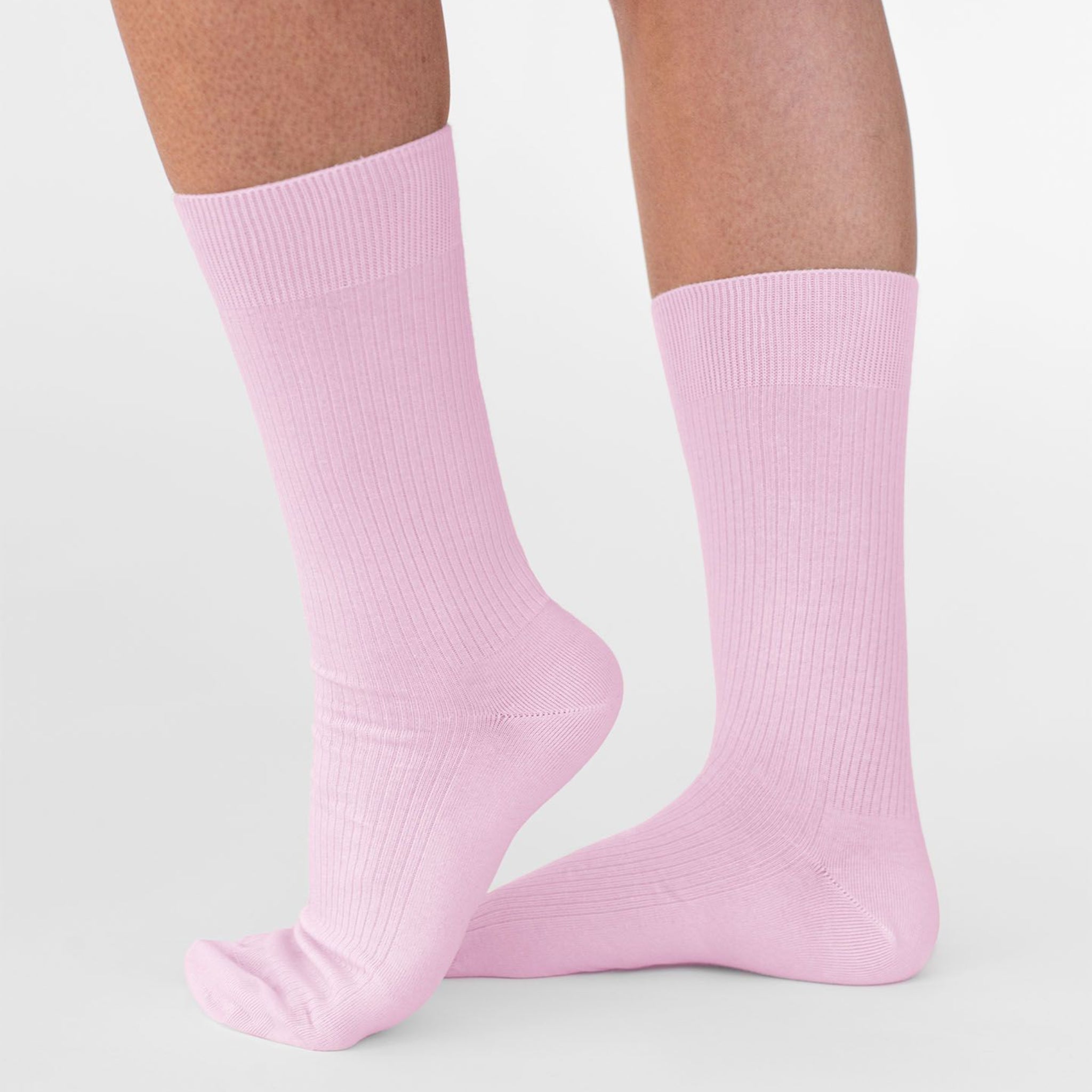 Zwei Beine in rosa Socken auf hellem Hintergrund.