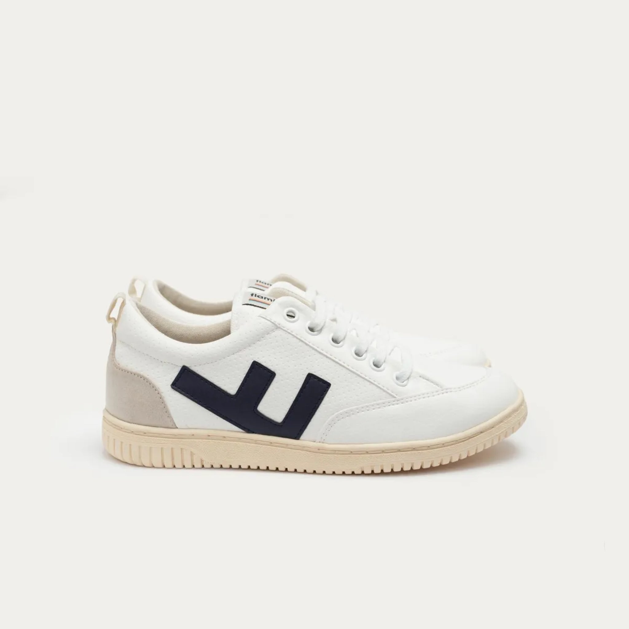 Weiße Sneaker mit dunkelblauem Logo an der Seite und beiger Sohle, auf einer neutralen Hintergrundoberfläche.