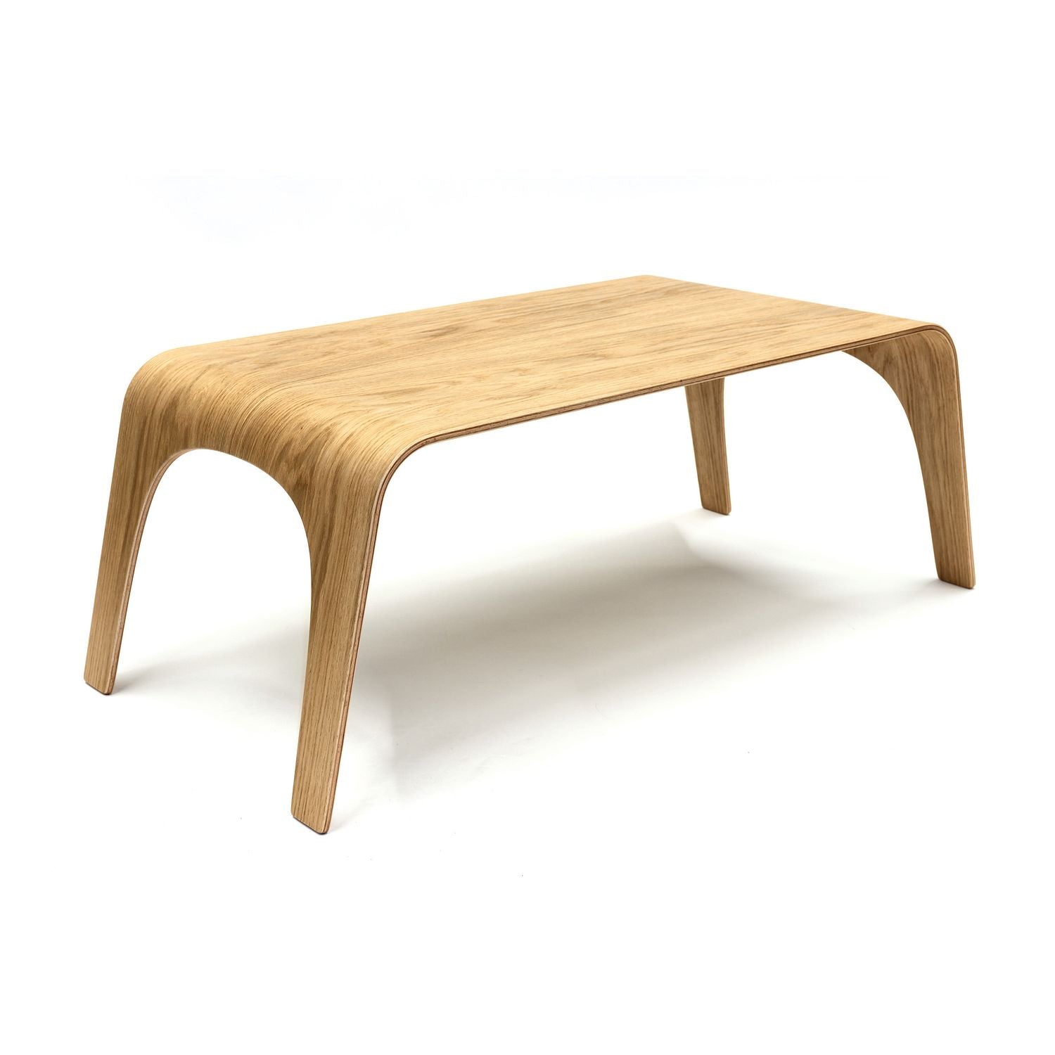 Moderner, niedriger Tisch aus gebogenem Holz mit glatter Oberfläche und abgerundeten Ecken.