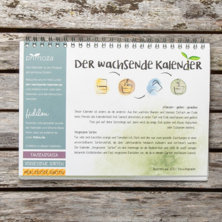 Kalender auf Holzuntergrund zeigt "Der wachsende Kalender" mit Illustrationen und Text über das Pflanzen von Blumensamen.