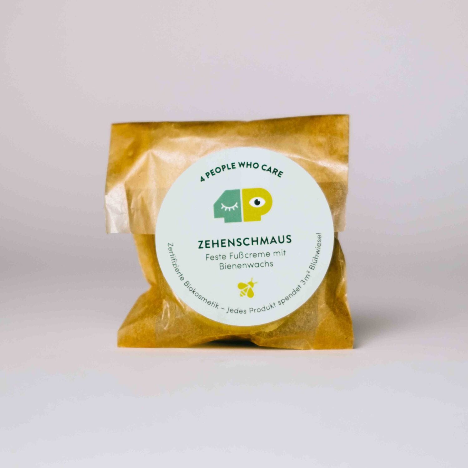 Verpackung mit Bienenwachs-Fußcreme "Zehenschmaus" von "4 People Who Care" auf einem hellen Hintergrund.