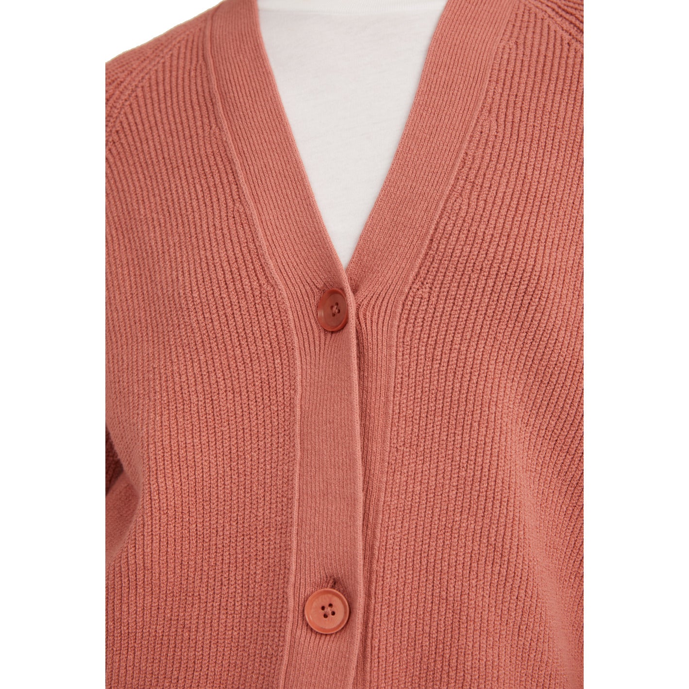 Rosa Strickjacke mit zwei Knöpfen und feinem Rippenmuster, getragen über einem weißen Oberteil.