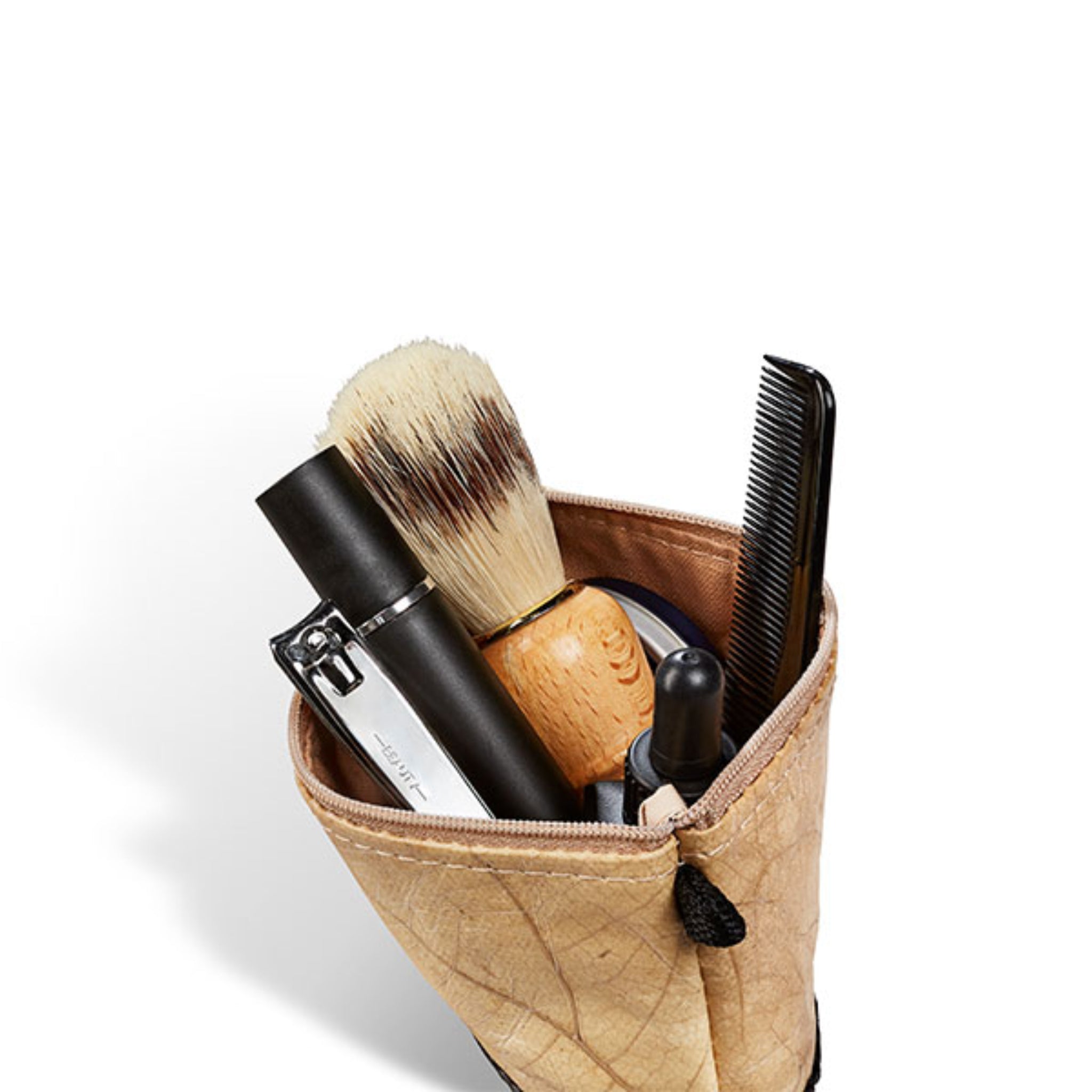 Kulturbeutel mit Rasierpinsel, Lippenbalsam, Nagelknipser, Kamm und einer kleinen Flasche auf weißem Hintergrund.